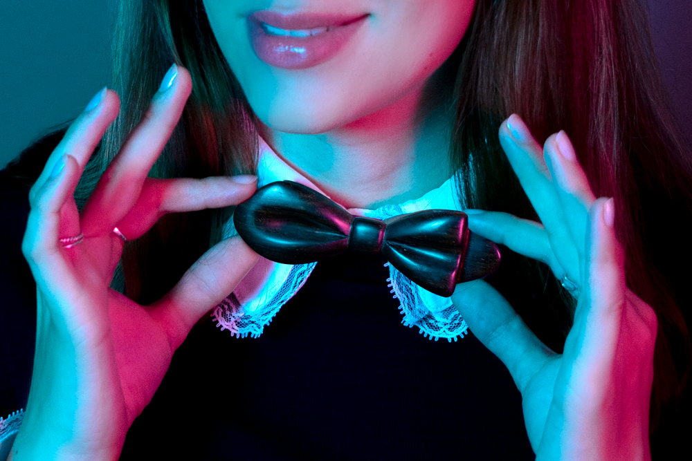 Gros plan sur une femme portant un col de chemise blanche et un pull noir avec un noeud papillon en bois Lysandra Dalbergia Maison Tessier