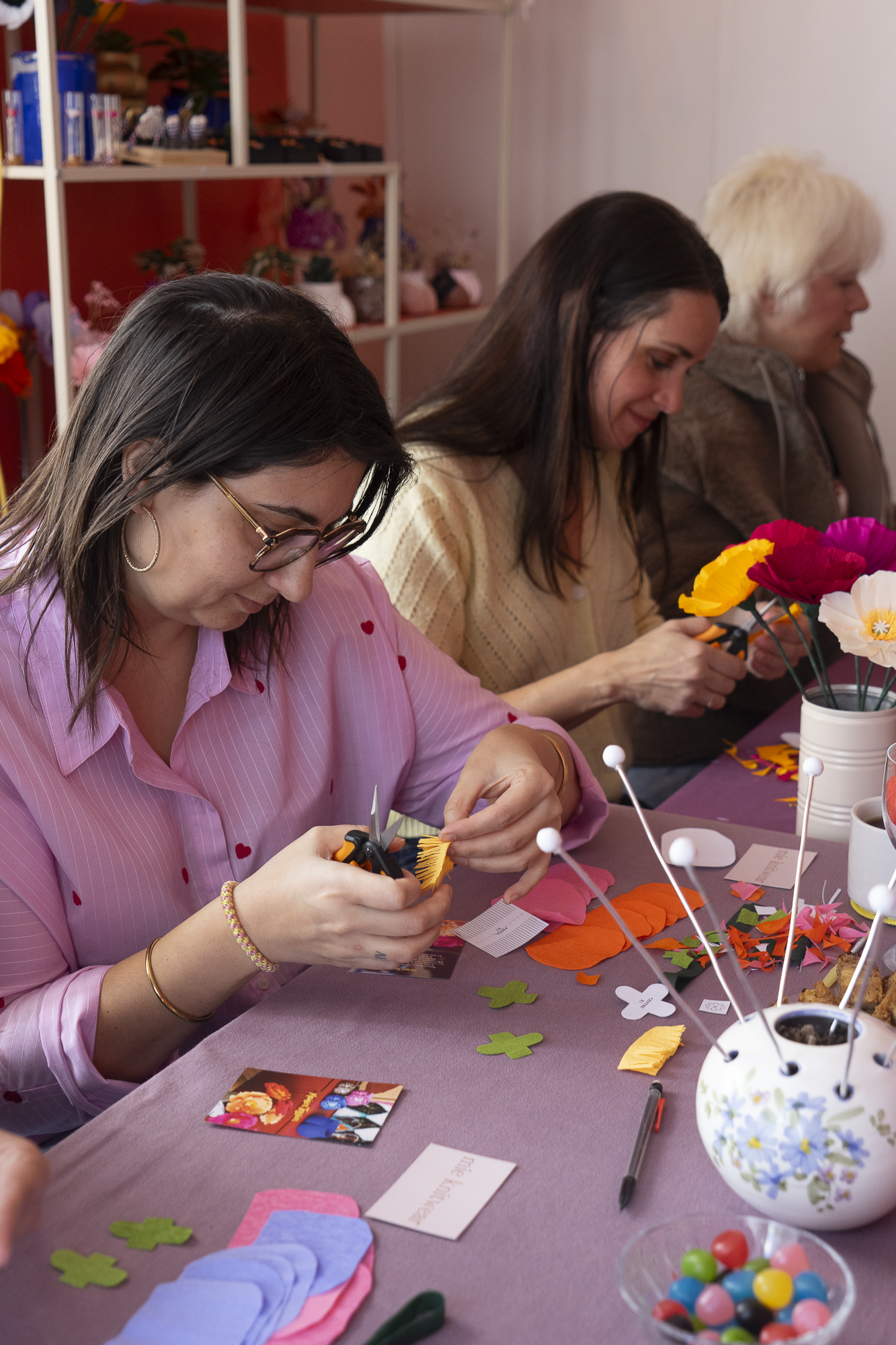 Deux participantes concentrées découpant et disposant sur la table du papier crépon pour créer des Pavots en papier lors d’un atelier, team building, EVJF, animé par Maison Tessier.
