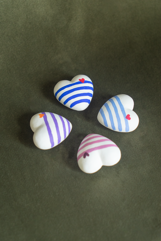 Collection des 4 Magnets Mini Coeur Marinière placés en carré sur un fond vert olive, disponibles en cobalt, en violet, en outremer et en rose, déco parfaite pour un frigo et accrocher vos photos, fabriqués en résine écologique avec amour par Maison Tessier.
