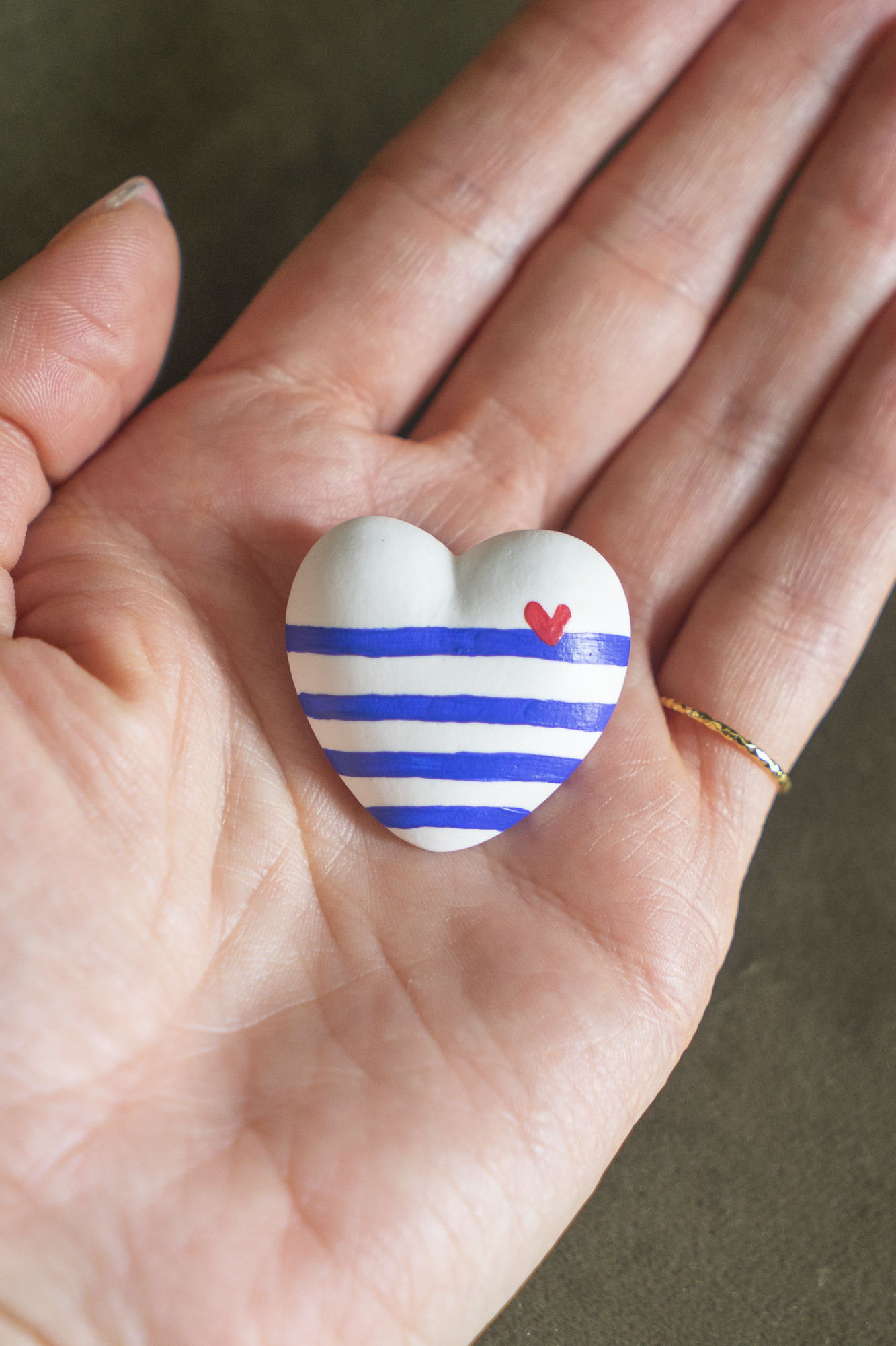 Magnet Mini Cœur Marinière Cobalt en résine écologique, petit coeur bombé avec rayures bleu Klein, bleu Majorelle, avec un petit coeur rouge sur la ligne à droite, tenu dans une paume de main pour illustrer sa taille réelle, accessoire déco original et marin fait main par Maison Tessier