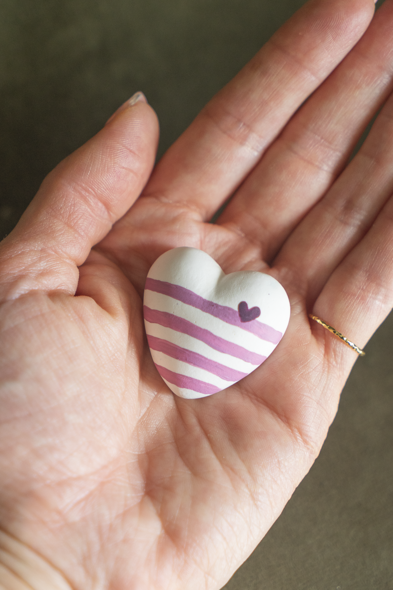 Magnet Mini Cœur Marinière Rose en résine écologique, petit coeur bombé avec rayures roses, avec un petit coeur rose foncé sur la ligne à droite, tenu dans une paume de main pour illustrer sa taille réelle, accessoire déco original et marin fait main par Maison Tessier.