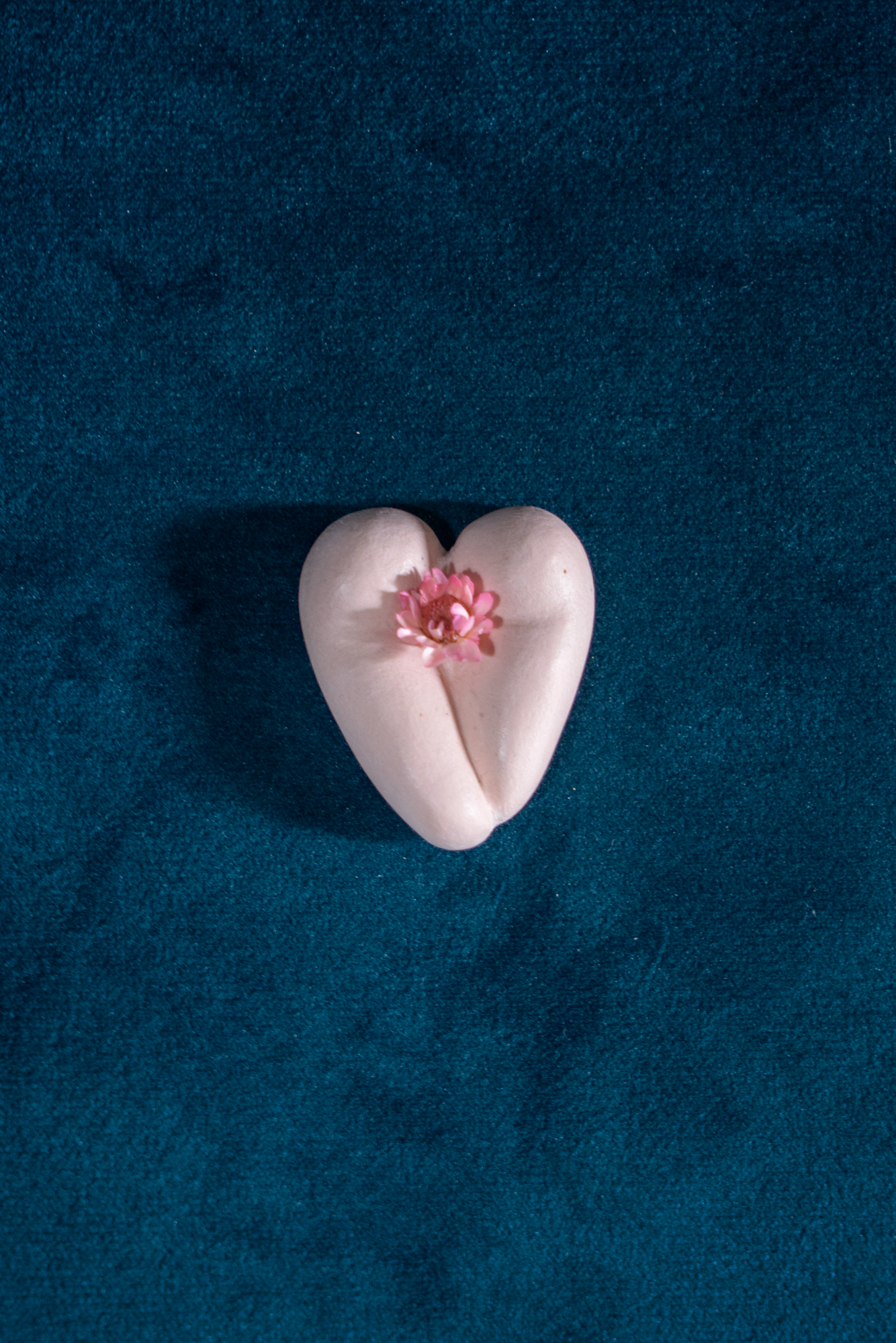 Coeur à nu de Maison Tessier, crème, fesses en forme de coeur avec petite fleur rose, sur une main
