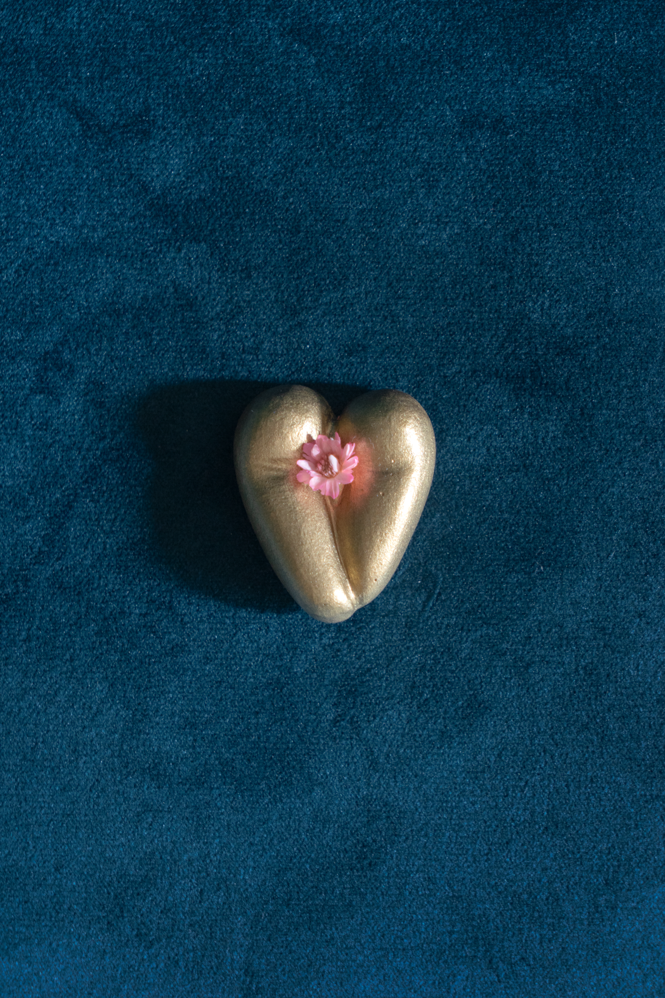 Coeur à nu de Maison Tessier, doré, fesses en forme de coeur avec petite fleur rose, sur une main