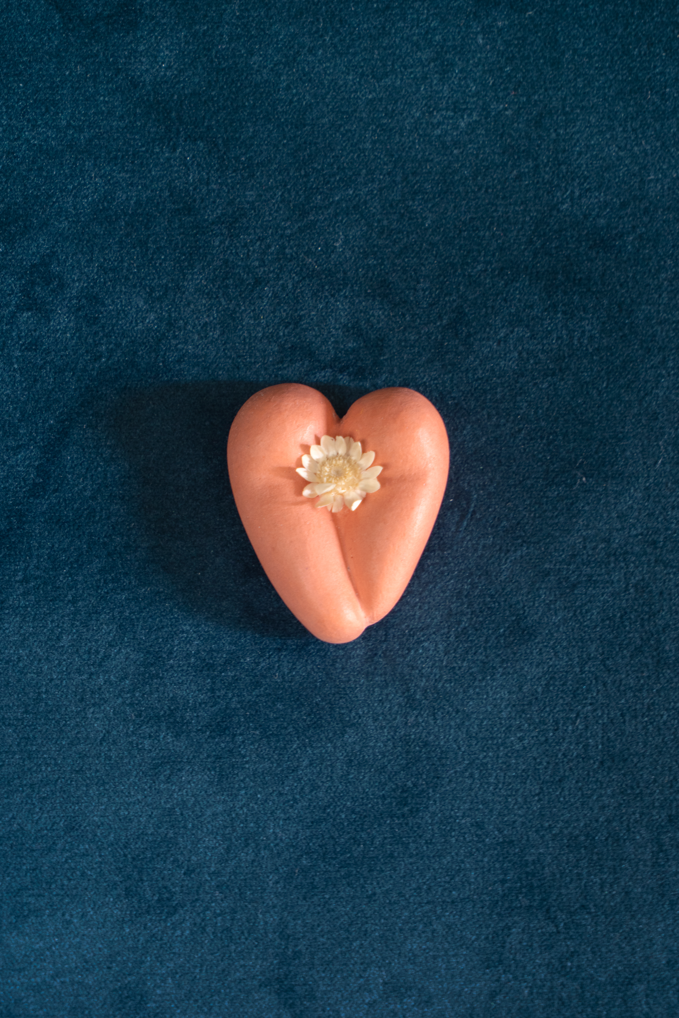 Coeur à nu de Maison Tessier terracotta, fesses en forme de coeur avec petites fleurs séchées, sur tissus velour émeraude