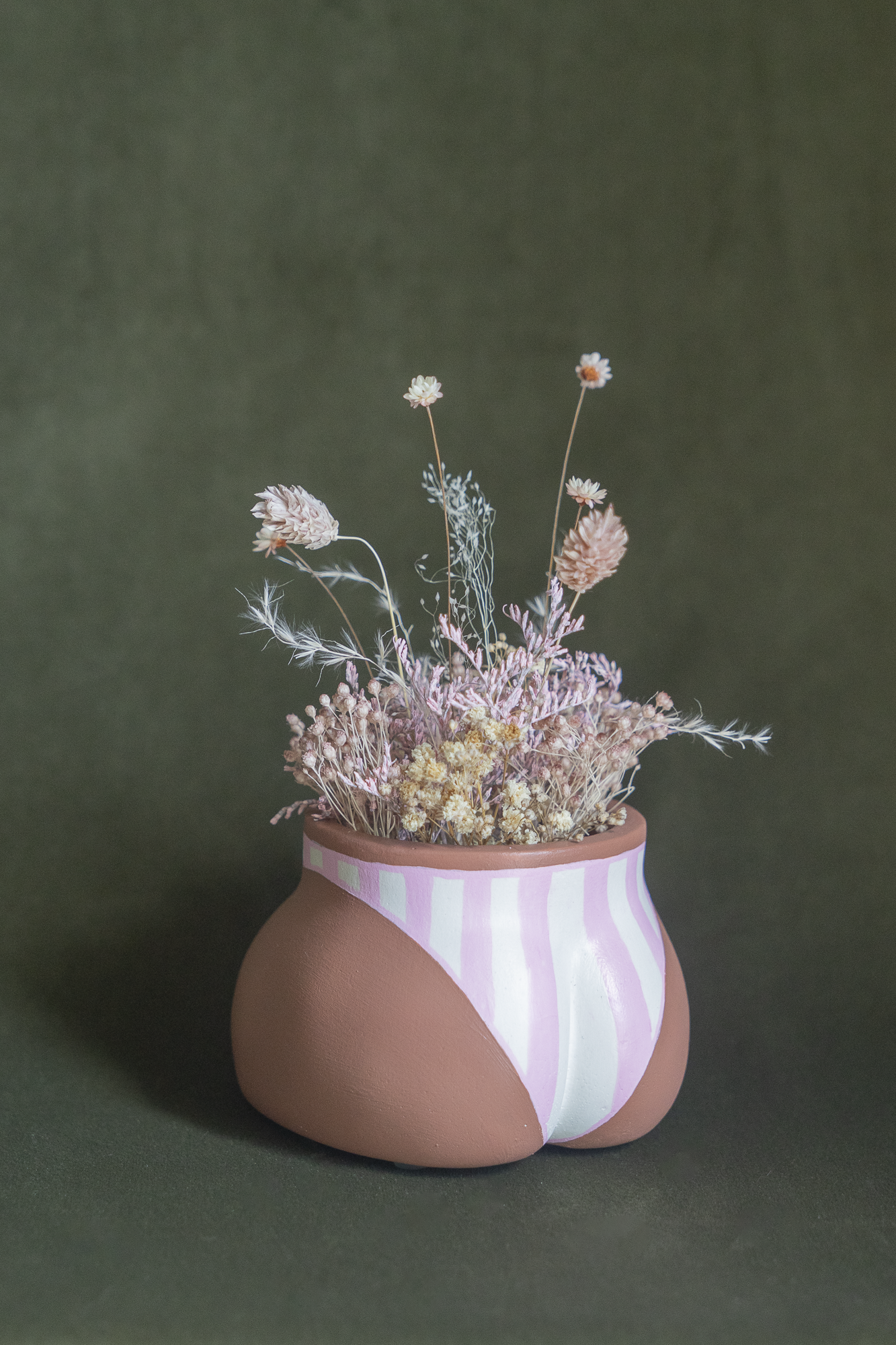 Mini cache-pot Fessier en résine écologique, côté fesses, couleur peau avec un maillot rayures rose et blanc garni d'un bouquet de fleurs séchées avec lagures, gypsophiles, glixias, phalaris rose poudré et blanches sur fond kaki, objet déco floral original fait main par Maison Tessier