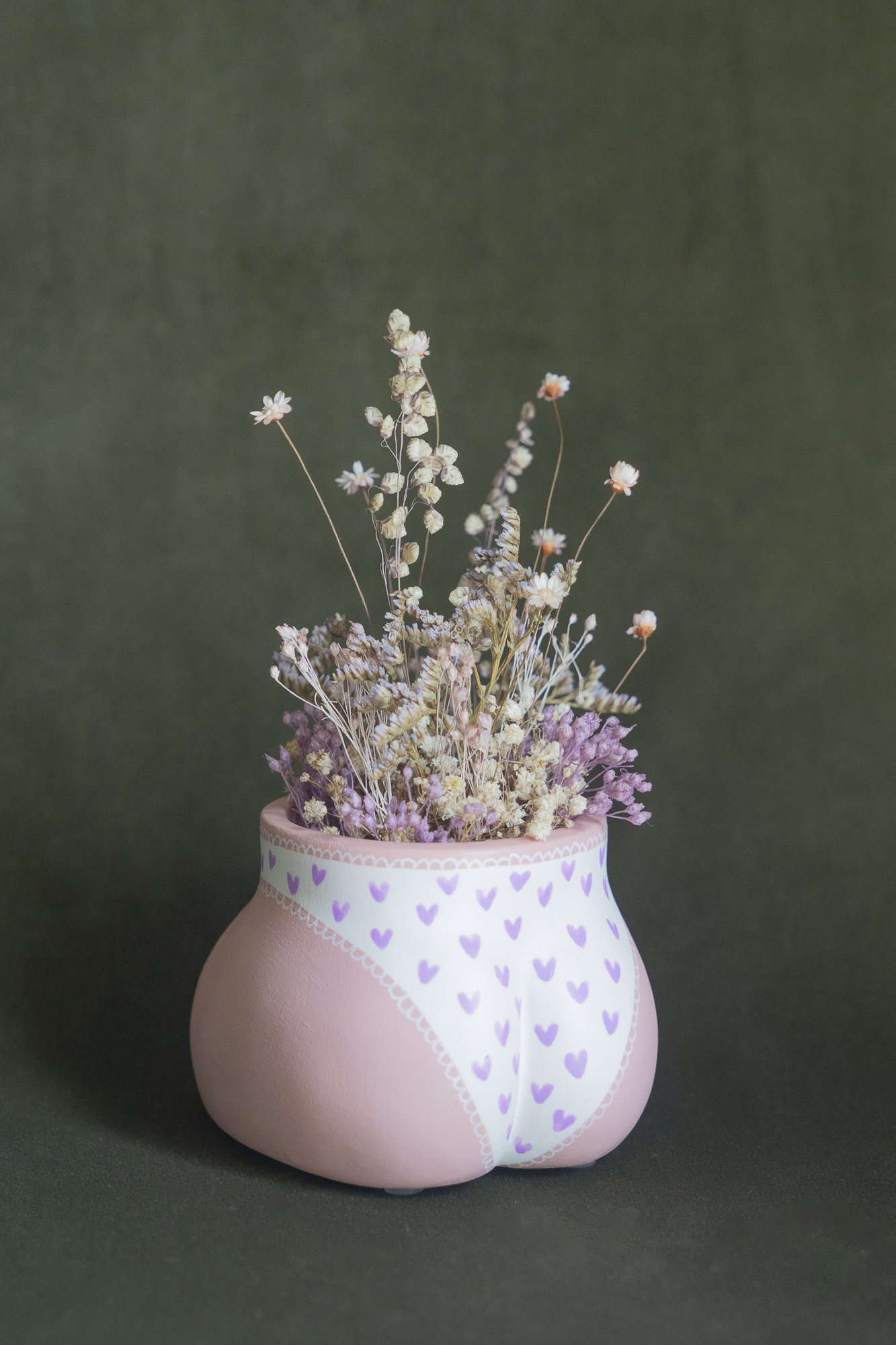 Mini cache-pot Fessier en résine écologique, côté fesses, couleur peau avec une culotte blanche à cœurs violets garni d'un bouquet de fleurs séchées avec lagures, gypsophiles, glixias, phalaris, hortensias mauves et blanches sur fond kaki, objet déco floral original fait main par Maison Tessier