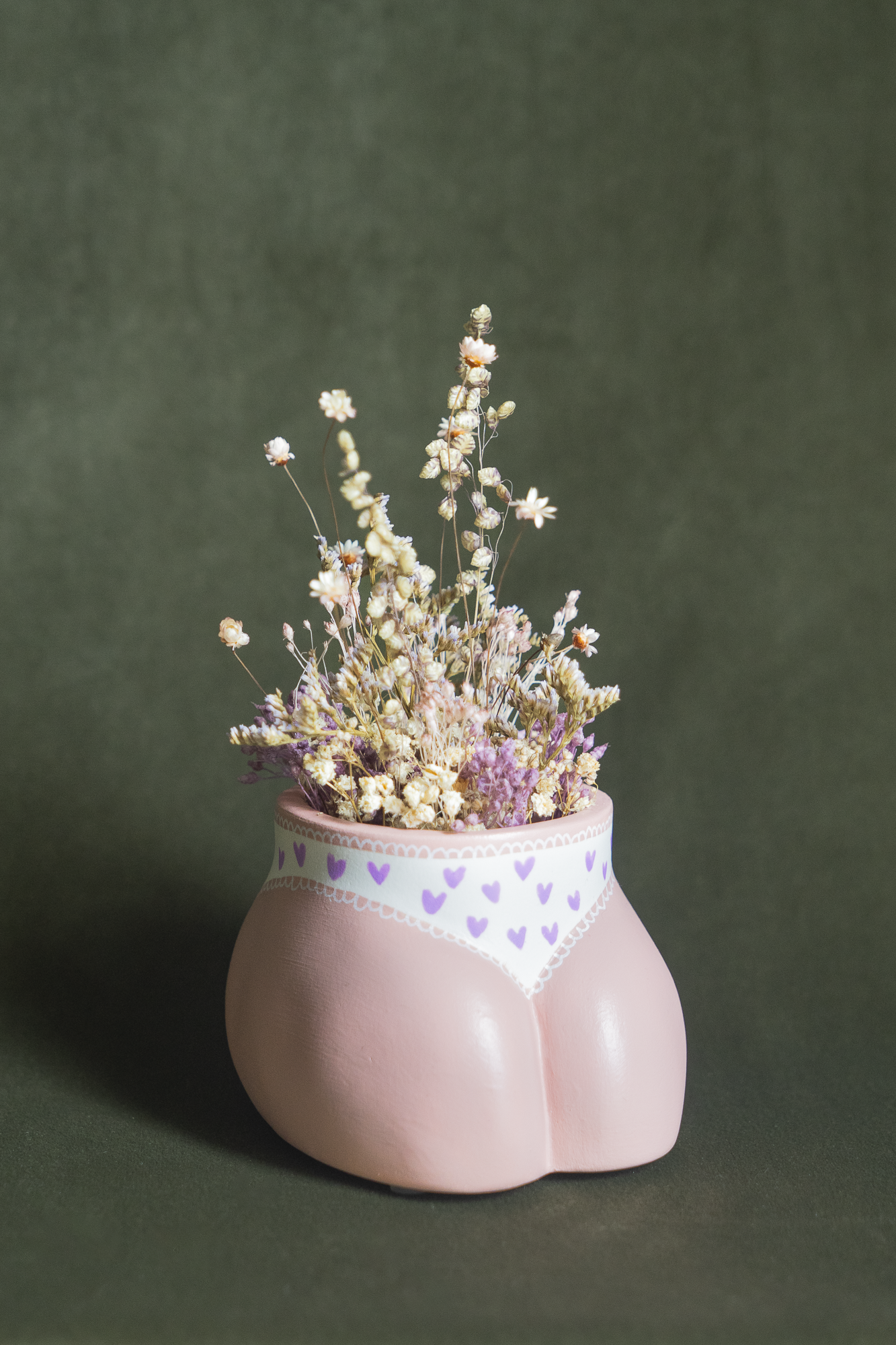 Mini cache-pot Fessier en résine écologique, côté pubis, couleur peau avec une culotte blanche à cœurs violets garni d'un bouquet de fleurs séchées avec lagures, gypsophiles, glixias, phalaris, hortensias mauves et blanches sur fond kaki, objet déco floral original fait main par Maison Tessier