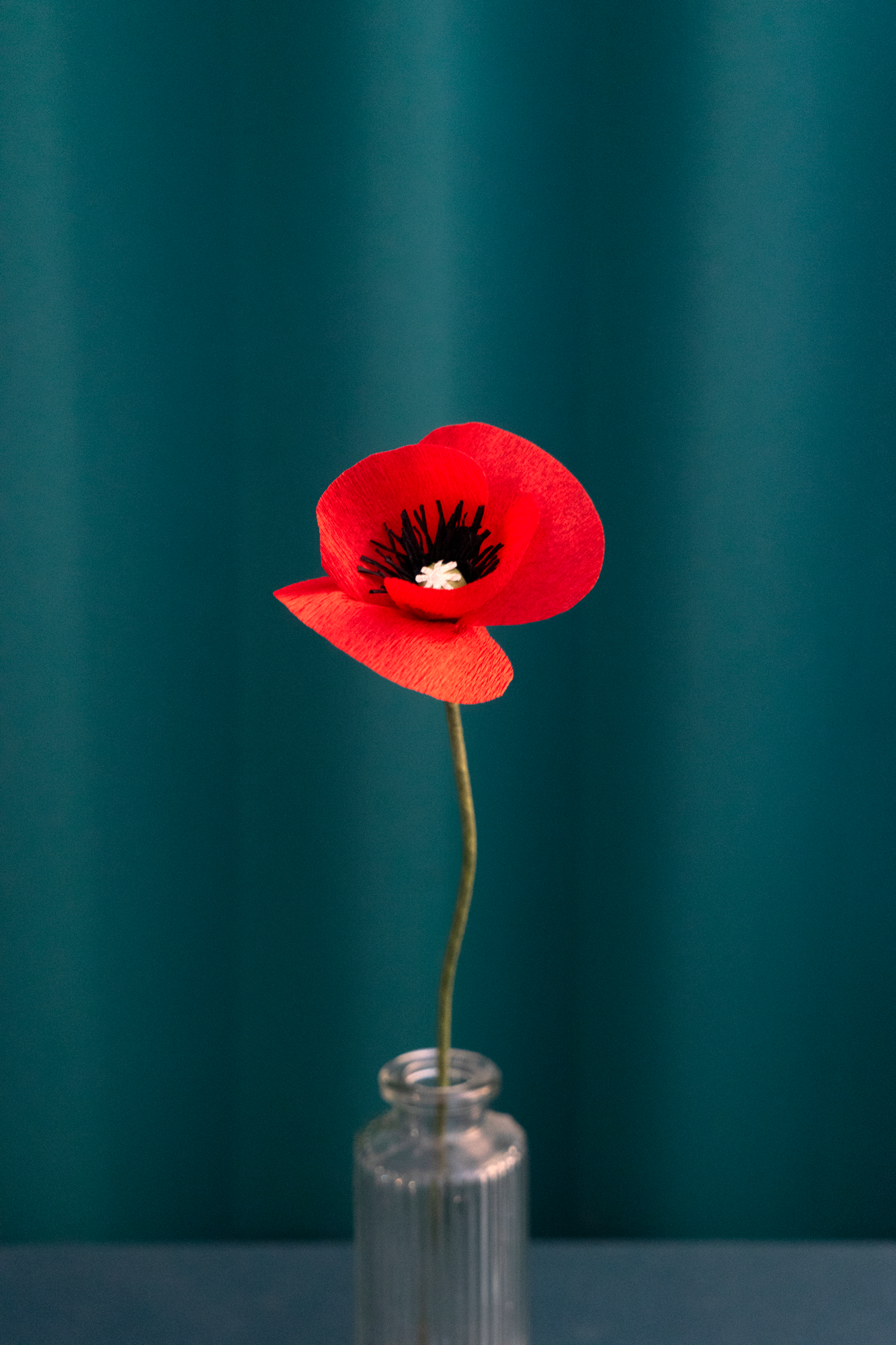 Fleur en papier Coquelicot, dans un vase sur un fond couleur vert émeraude