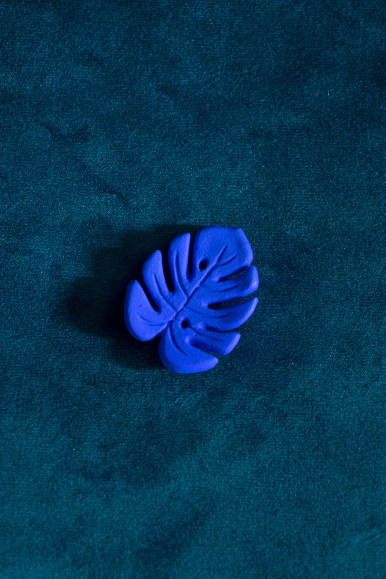 Mini Monstera Bleu Klein broche de Maison Tessier, sur fond vert émeraude