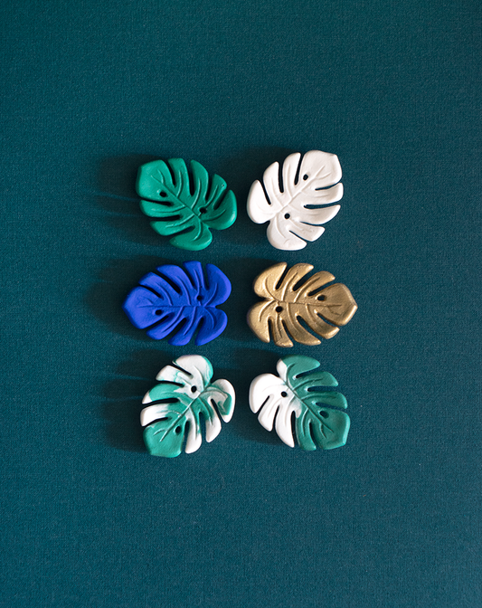 Six Mini Monstera magnets de Maison Tessier en émeraude, variegata panachée, variegata bicolore, dorée, Blanc, Bleu Klein sur fond vert émeraude