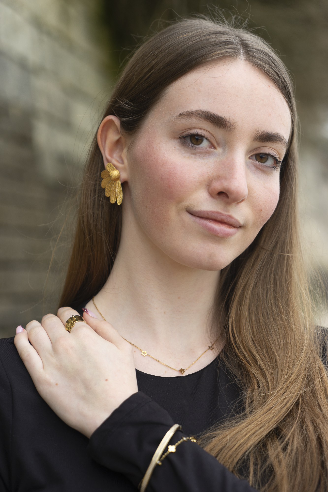 Femme portant des boucles d’oreilles, Puces Pâquerrettes or, en papier crépon fait main, bijoux floraux artisanaux fabriqués par Maison Tessier.