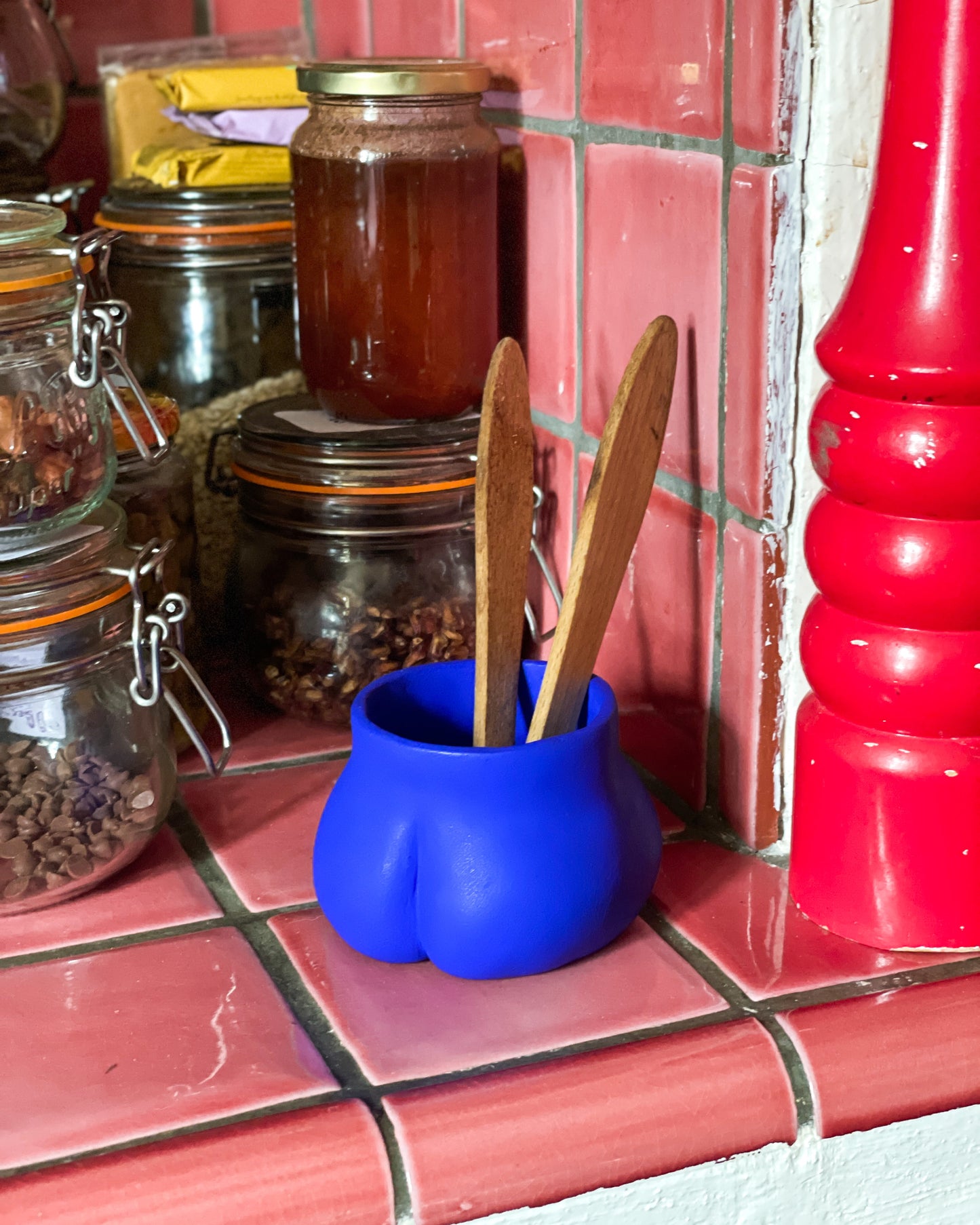 Le Mini Fessier Bleu Klein servant de pot à ustensiles dans une cuisine