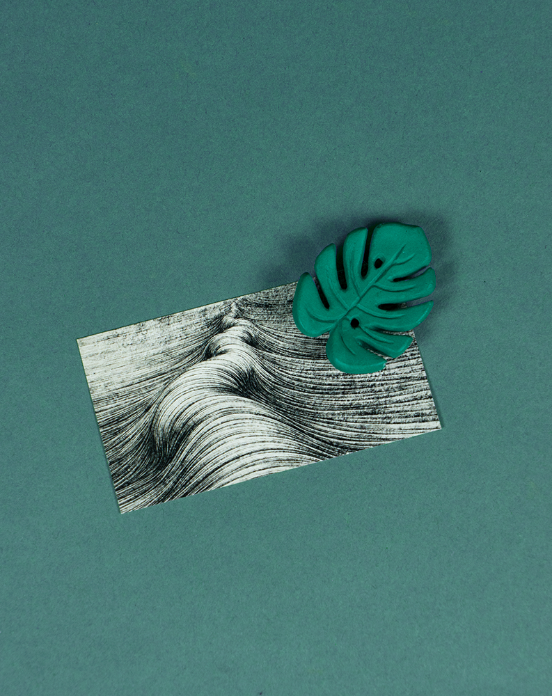 Mini Monstera Emeraude magnet de Maison Tessier, sur fond vert émeraude avec carte de visite