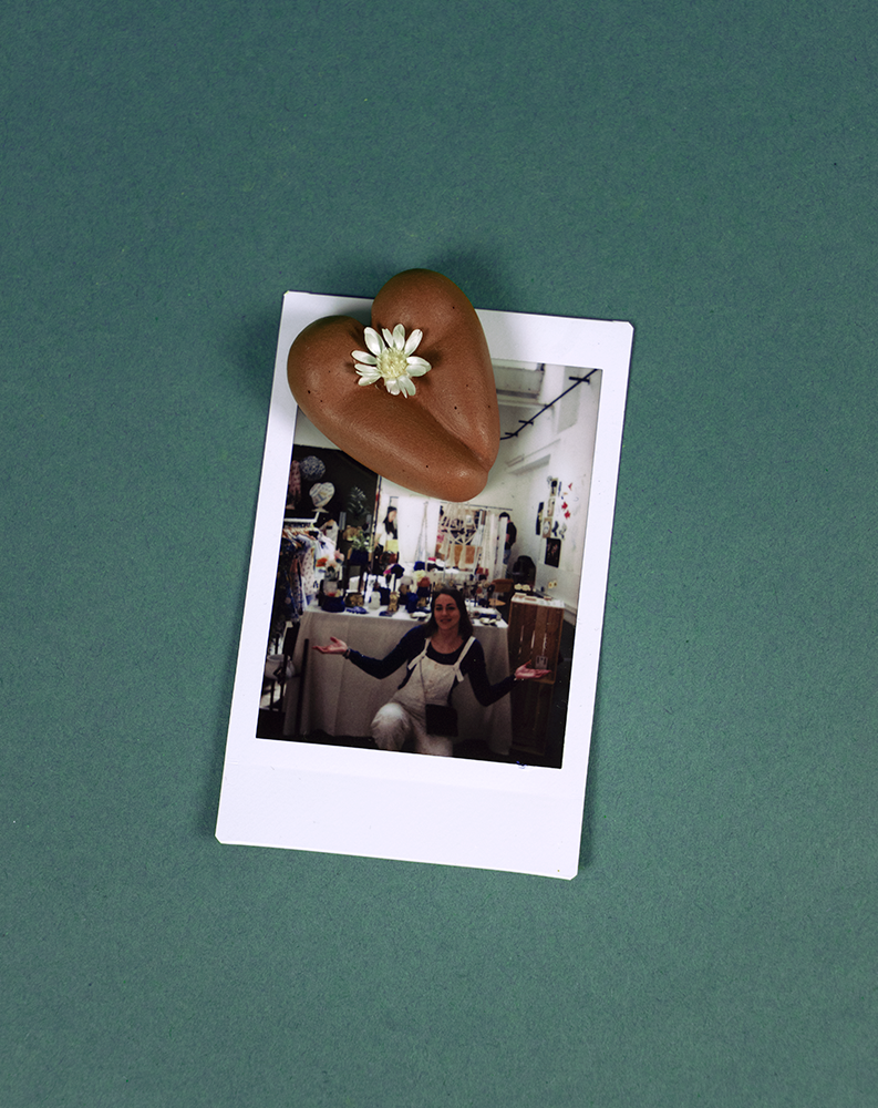 Coeur à nu de Maison Tessier, chocolat, fesses en forme de coeur avec petite fleur blanche, sur fond vert émeraude avec polaroïd