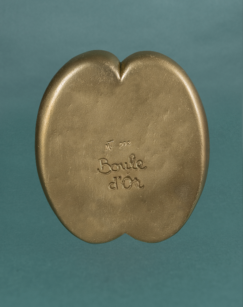 Exemple de gravure personnalisée "Boule d'Or" sous le pot Petit Fessier de Maison Tessier couleur Dorée, sur fond vert émeraude