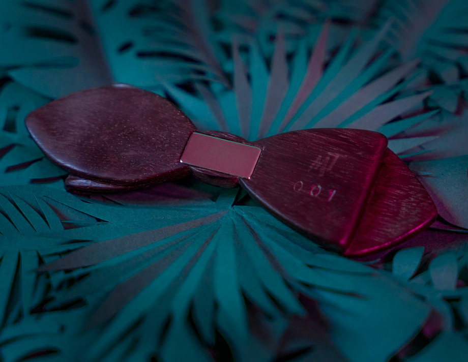 Vue arrière du noeud papillon en bois Maison Tessier en Amarante sur fond de feuilles tropicales en papier, vue de 3/4