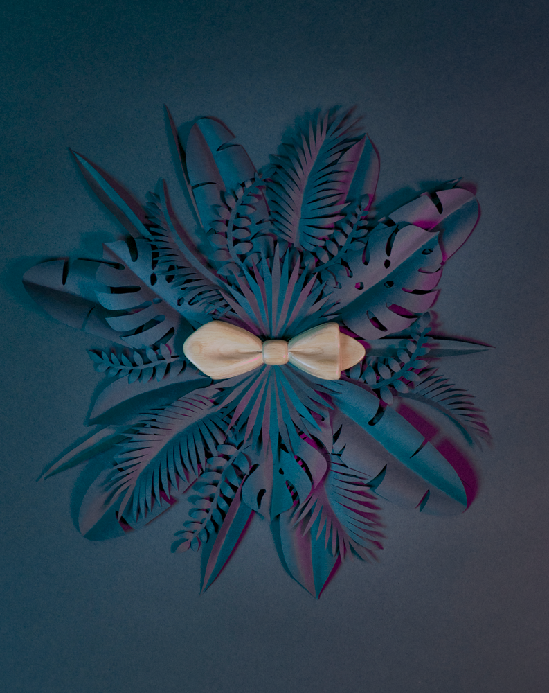 Noeud papillon en bois Maison Tessier en Châtaignier sur fond de feuilles tropicales en papier en forme de rosace, vue de dessus