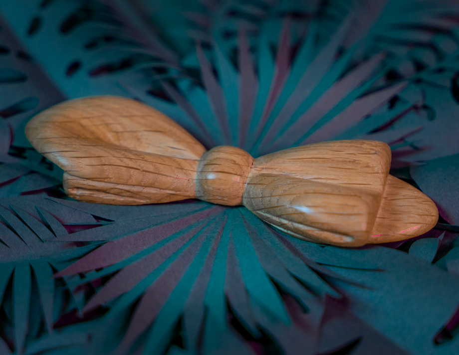 Noeud papillon en bois Maison Tessier en Chêne sur fond de feuilles tropicales en papier, vue de 3/4